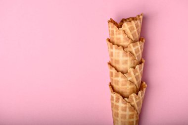 Dört gevrek waffle külahı canlı pembe bir arka plana karşı güzelce istiflenmiştir. Dondurma ikram etmek için mükemmeldir..