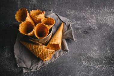 Nötr desenli bir arka planda bir waffle külahı koleksiyonu sergilenir, gıcır gıcır dokularını gösterir ve kapakları doldurmaya hazırdır.