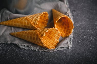 Üç boş waffle külahı, sıcak ve davetkar bir atmosferde bir top taze dondurmayı bekliyor..
