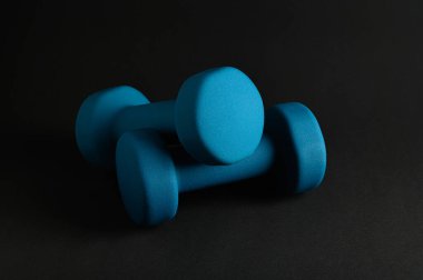 Parlak mavi vinil halterler koyu bir yüzeyde dinleniyor, etkin çalışmalar için ergonomik tasarımlarını sergiliyorlar..