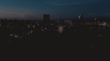 Mexico City 'de gece hayatı, mavi saatte ışıklar yanıp sönmeye başlar ve Meksika' daki gökdelen dünya ticaret merkezi Dolly Zoom yakınlarında bir uçağın geçtiği görülmektedir.