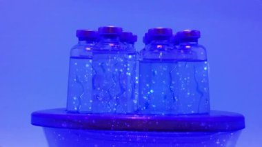 Ultraviyole ışık altında çözelti aşısı olan steril laboratuvar şişeleri. Grip H5N1 'i kontrol etmek için C tipi bilimsel konsept. Kamera hareketine bakın.