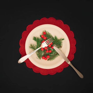 Noel yemeği konsepti. Gümüş çatal bıçak takımı, Noel ağacı dalları ve siyah arka planda kırmızı böğürtlen. Noel ve Yeni Yıl geçmişi.