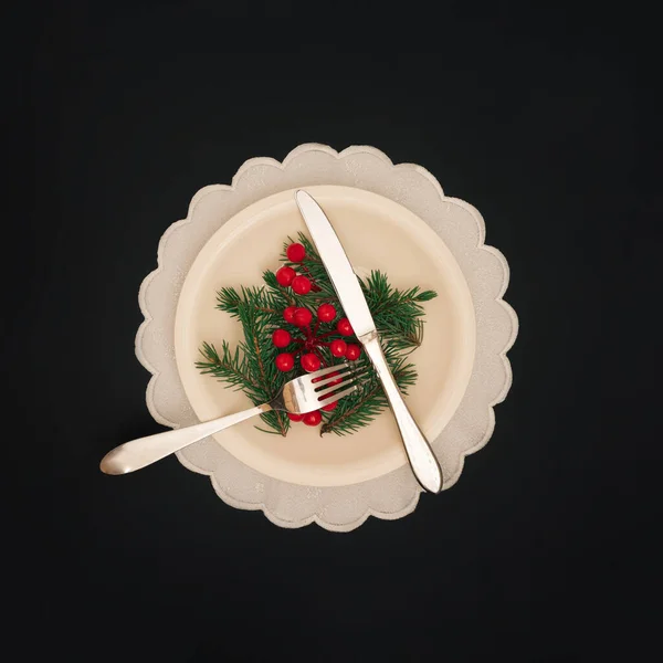クリスマスディナーのコンセプト 黒い背景の上に銀のカトラリー クリスマスツリーの枝と赤い果実 クリスマスと新年の背景 ロイヤリティフリーのストック画像