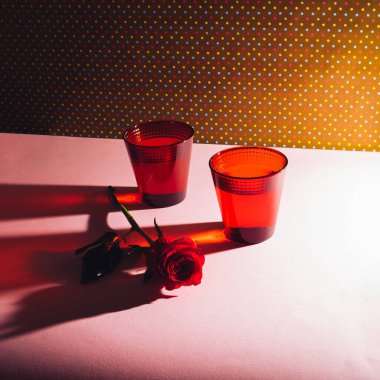 İki kırmızı gözlük ve bir kırmızı gülün yaratıcı romantik kompozisyonu. Estetik Retro Sevgililer Günü konsepti.