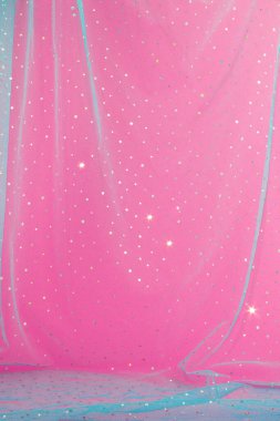 Abstract pink background with blue tulle and sequins.