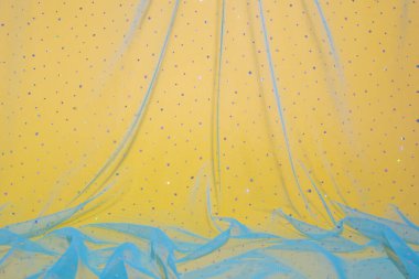 Elegant wallpaper made of turquoise tulle fabric with sequins on bright yellow background. Aesthetic fashion and love design.