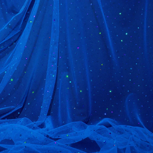 Aesthetic, elegant dark blue tulle fabric with sequins on black background. Starry night composition.