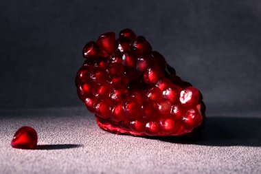 Gri arka planda bir dilim kırmızı olgun nar. Mevsimlik kış meyveleri. Demirin kaynağı.