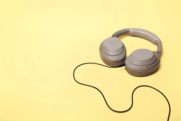 Light gray wireless on-ear headphones with the ability to connect via wire on a sand-colored background. Headphones for playing games or listening to music. Noise canceling headphones. Top view. Copy space
