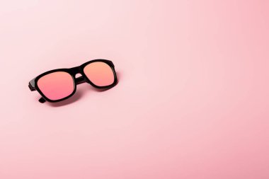 Black sunglasses with Multicolor Mirror Lens on pink background. Polarized sunglasses with UV protection. Copy space.