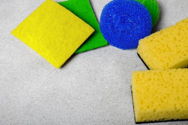 multi-colored different tipes of dishwashing sponges and napkins on grey background. The topic of proper dish washing. House cleaning