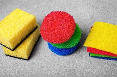 multi-colored different tipes of dishwashing sponges and napkins on grey background. The topic of proper dish washing. House cleaning