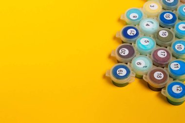 Rakamlara göre resim. Tuvale resim çiziyorum. Numaralı boya kutuları. Yaratıcı hobi. Yeni başlayanlar için resim yapmak. Acemi sanatçı. Sanat fikri. Sarı arka planda numaralandırılmış boyalar..