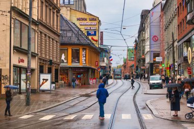Oslo, Norveç - 25 Nisan 2012: Yağmur yağdığında sokak manzarası... bir geçitten geçen arabalar, yayalar ve bir tramvay
