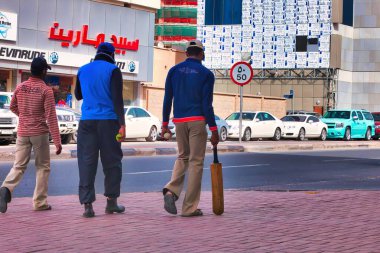 Doha, Katar - 26 Ocak 2010: Cuma namazında işçiler izinli ve sokakta bekliyorlar veya kriket oynuyorlar