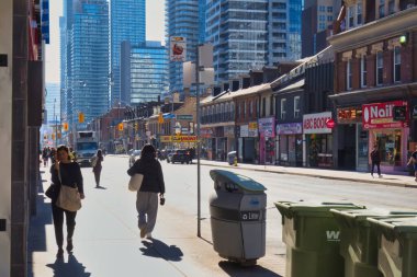 Toronto, Canada - 24 October 2022: people walking on the sidewalk of a street downtown with shops and store front around