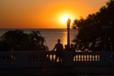 Colonia del sacramento, uruguay - Kasım 12022: UNESCO dünya mirası kasabasının tahta kaldırımında dikilen insanlar Rio de la Plata üzerinde günbatımının keyfini çıkarıyorlar.