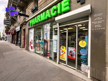 Paris, Fransa - 11 Nisan 2023: büyük yeşil bir eczane tabelası tıbbi bakım ürünleri satan bir mağazanın girişinde asılı duruyor.