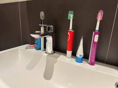 Hollanda, den haag - Nisan 08 2023: renkli diş fırçaları küçük diş macunlarıyla dolu bir banyoda lavaboya dizilmiş.