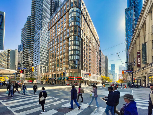 Торонто, Канада - 24 октября 2022 года: люди, идущие по пешеходному переходу улицы в центре города с магазинами и магазинами вокруг