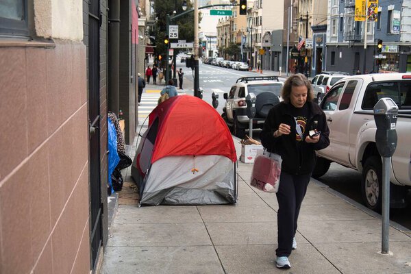 San Francisco, United States - February 13 2020 : a homeless person lives in a tent in the middle of the sidewalk downtown san francisco