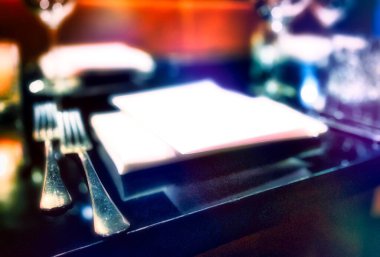 Peçeteler, gümüş eşyalar ve menü kartlarıyla hazırlanmış lüks bir masa.