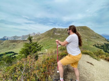 Bir yürüyüşçü bir zirvede durmuş vadinin manzarasına bakıyor.