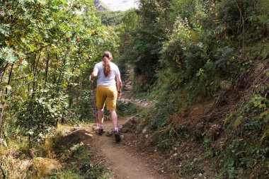 a hiker with stick is walking on a mountain trail high in the mountains