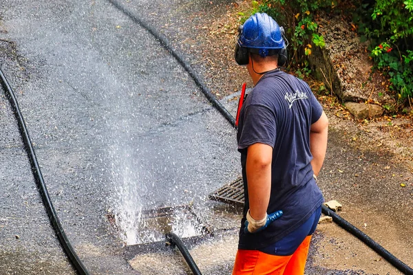 stock image Menthon Saint Bernard, France - September 09 2021: a professional worker is busy with a pump car and a hose under high pressure cleaning a sewer tube