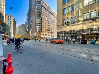 Toronto, Kanada - 24 Ekim 2022: Bir bisikletçi alışveriş merkezleri ve etrafındaki büyük binalarla kalabalık bir caddede ilerliyor