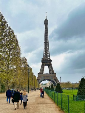 Paris, Fransa - 10 Nisan 2023: Eyfel Kulesi 'nin eteğindeki Champ de Mars parkında bir turist yürüyor.