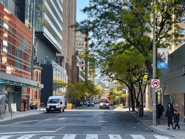 Toronto, Canada - 24 October 2022: people walking on the sidewalk of a street downtown with shops and store front around