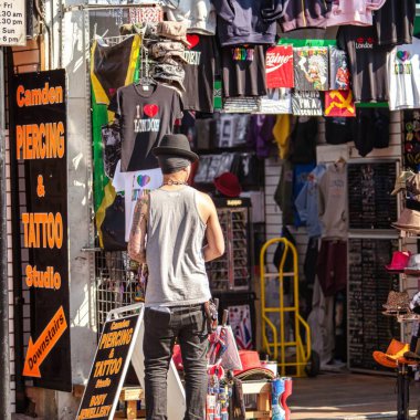 Londra, Birleşik Krallık - 18 Mart 2009: Renkli Camden yol pazarındaki hediyelik eşya dükkanının önünde şapka ve gömlek satan bir adam