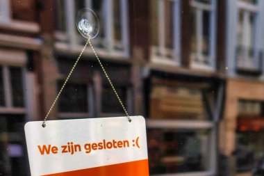 Lahey, Hollanda - 03 Ocak 2022: Hollandalı dilinde kapalı olduğumuza dair bir işaret bir dükkan veya restoranın giriş kapısına yapıştırılmıştır.