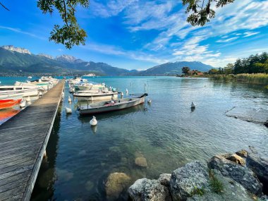 Annecy, Fransa - Ekim 01 2021: Kristal berrak alp gölü boyunca lüks tekneleri olan bir rıhtım veya iskele.
