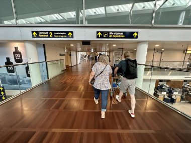 Kopenhag, Danimarka - 26 Temmuz 2023: Havaalanının modern terminal binasındaki yolcular uçağa binebilecekleri kapıya doğru yürüyorlar.