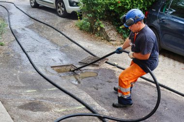 Menthon Saint Bernard, France - September 09 2021: a professional worker is busy with a pump car and a hose under high pressure cleaning a sewer tube clipart