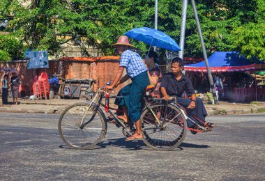 Yangon, Myanmar - Aralık 03 2012: İnsanlar toprak bir yolda sıcak bir günde triportör taksiyle taşınıyor.