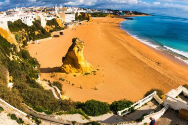 Albufeira, Portugal - January 18, 2016 : An overview of Albufeira beach. The rock on the beach in the middle of this wide angle picture. clipart