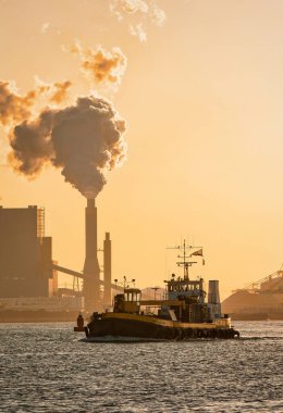 Rotterdam, Hollanda - 11 Kasım 2021: küçük bir römorkör bir petrol kimya fabrikasının gaz borusunun yanından geçiyor
