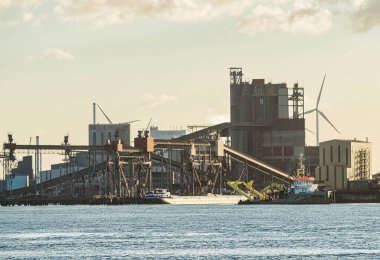 Rotterdam, Netherlands - November 11 2021 : iron ore is being unloaded by huge cranes in het industrial harbor clipart