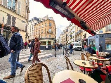 Paris, Fransa - 11 Nisan 2023: Saint Germain Pres Mahallesi 'nde bir Paris caddesinin kaldırımındaki bir bar veya restoranın masasında bir kadın oturuyor.