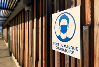 Menthon Aziz Bernard, Fransa - 21 Ekim 2021: Ahşap duvara asılmış bir Fransız tabelası maske görevi olduğunu gösteriyor.