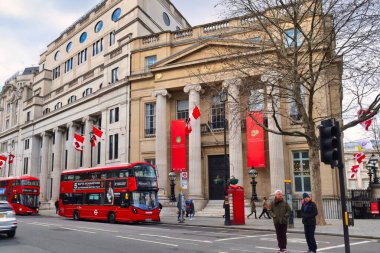 Londra, Birleşik Krallık - 6 Mart 2022: Kanada evlerinin bulunduğu Viktorya döneminden kalma kırmızı bir otobüs geçiyor