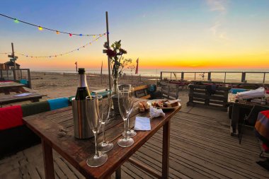 Zandvoort, Netherlands - March 26 2022: table with champagne bottle and glasses at a beach club at sunset