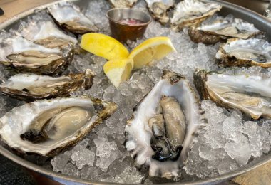 Den Haag, Hollanda - 18 Temmuz 2021: Limon ve baharatlı suazla birlikte buzda servis edilen bir istiridye deniz ürünleri tabağı