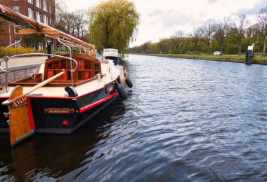 Voorburg, Hollanda - 04 Mayıs 2021: Nehir boyunca uzanan küçük bir köyün limanına tarihi bir ahşap tekne yanaştı.