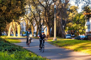 San Francisco, ABD - 11 Şubat 2020: Bu banliyölerdeki kasklarla birlikte San Francisco 'daki Panhandle' da sabah işe giderken bisiklet yolu üzerindeler.