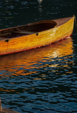 Talloires, France - September 08 2020 : an historic old wooden boat is seen floating in the harbor and docked clipart